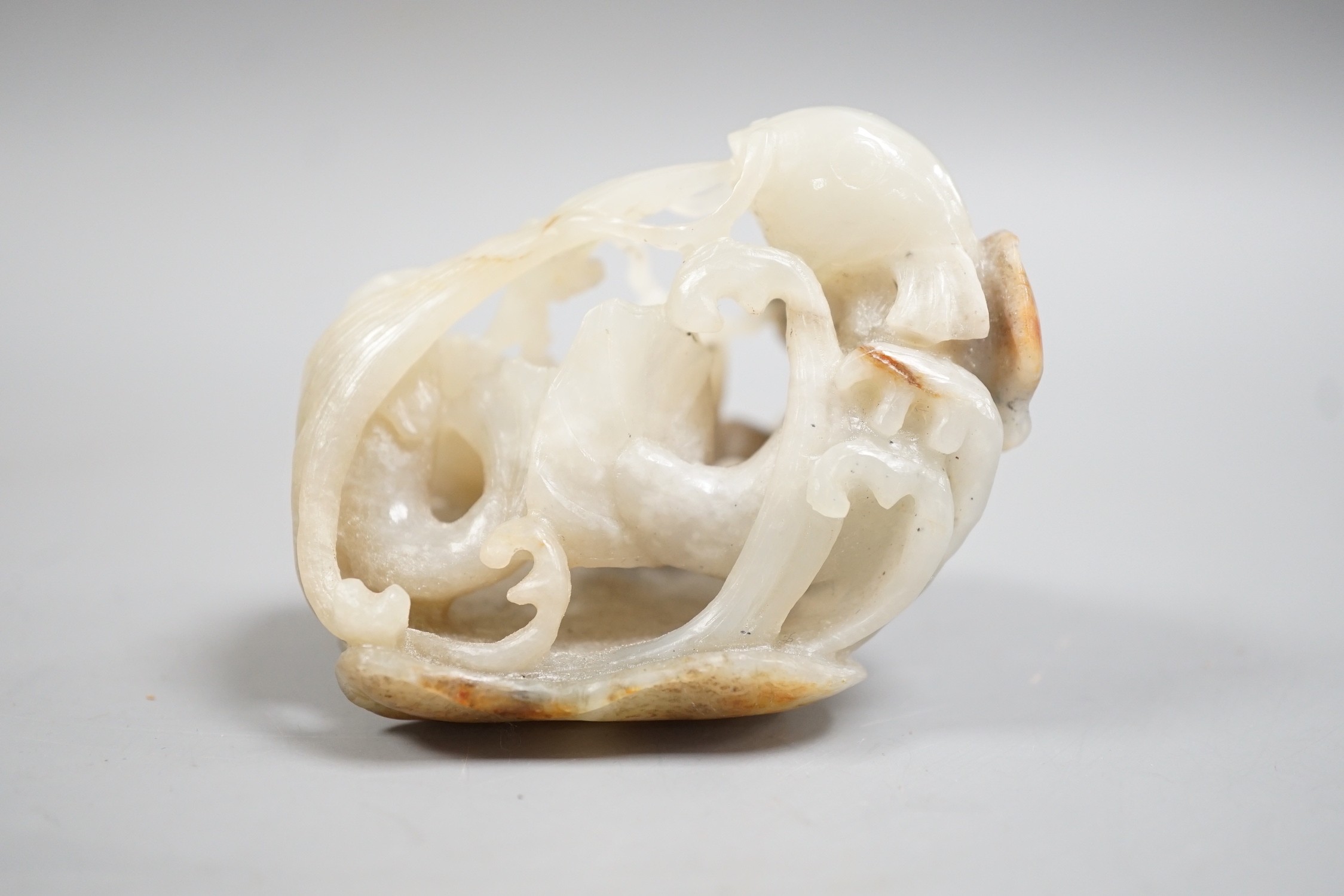 A Chinese pale grey and russet jade carving of carp amid lotus, 7.3 cm